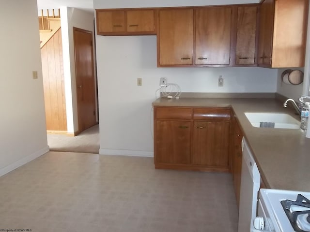 kitchen with a sink, baseboards, white appliances, and brown cabinets