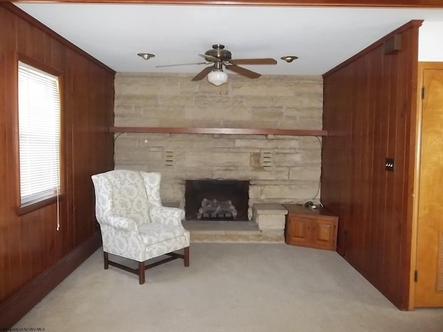 living area with a ceiling fan, a fireplace, light colored carpet, and wood walls