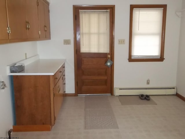 kitchen with a baseboard heating unit, light countertops, and baseboards