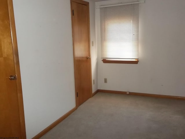 unfurnished room with baseboards and light carpet