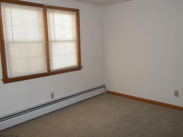 empty room featuring a baseboard radiator, baseboards, and light colored carpet