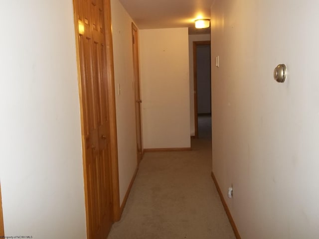 corridor featuring light colored carpet and baseboards