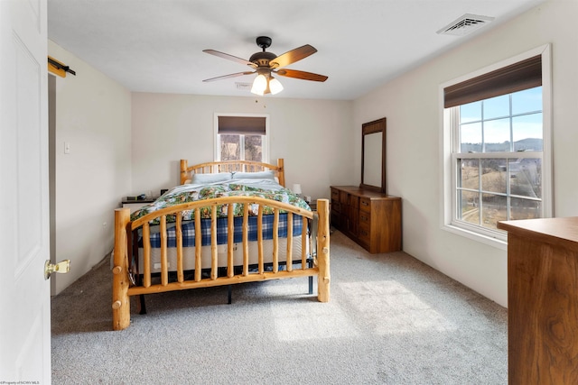 carpeted bedroom with a barn door, a ceiling fan, and visible vents