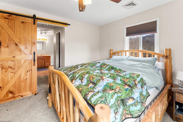 bedroom with a barn door, light carpet, visible vents, and ceiling fan