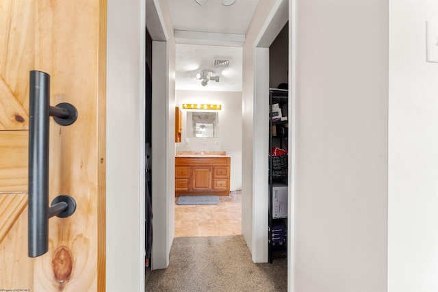 corridor featuring a sink, visible vents, and carpet floors