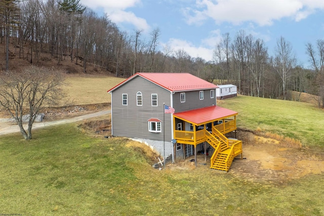 exterior space featuring a wooden deck, a lawn, metal roof, and stairs