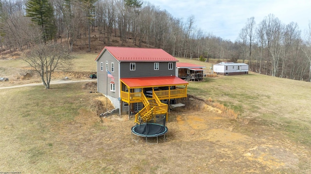 view of front of property with stairway, a front lawn, a trampoline, and metal roof