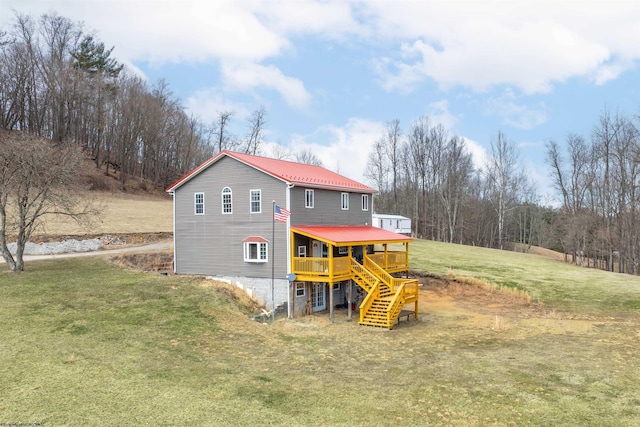 rear view of house featuring a deck, metal roof, stairs, and a yard