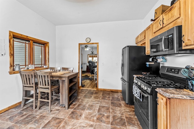 kitchen featuring appliances with stainless steel finishes, stone countertops, stone finish flooring, and baseboards