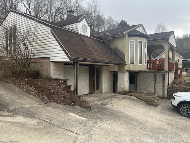 view of front facade featuring an attached garage, driveway, and roof with shingles