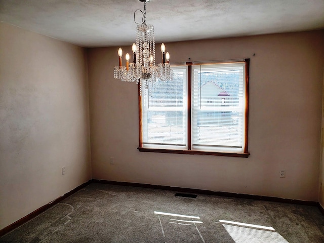 carpeted spare room featuring visible vents, baseboards, and a notable chandelier