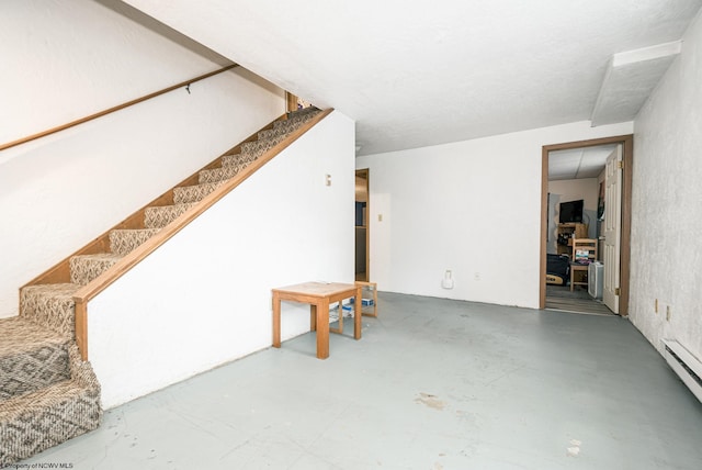 interior space featuring stairway, concrete floors, and a baseboard radiator