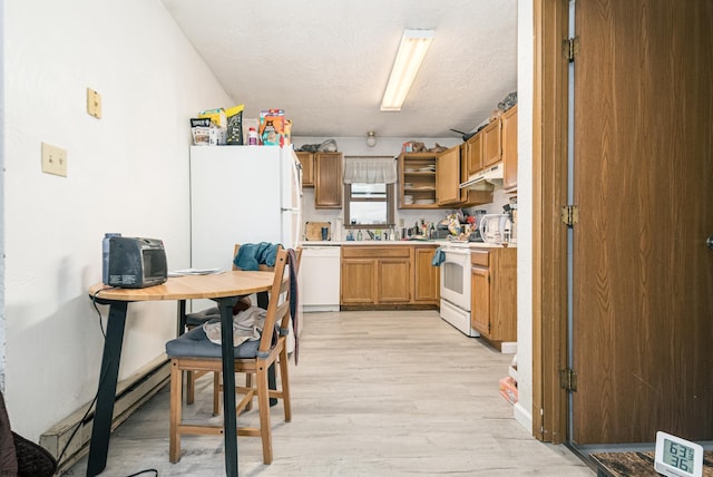 kitchen featuring brown cabinets, light wood-style flooring, under cabinet range hood, white appliances, and light countertops