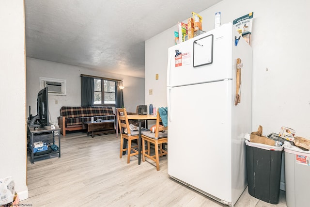 kitchen with a wall mounted air conditioner, light wood-type flooring, and freestanding refrigerator