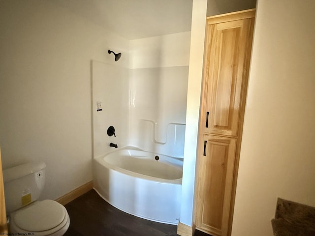 full bath with baseboards, toilet, and washtub / shower combination