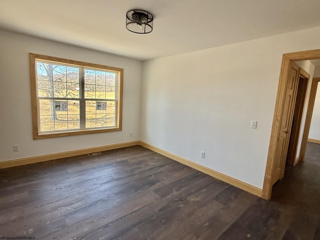 unfurnished room featuring visible vents, dark wood-style floors, and baseboards