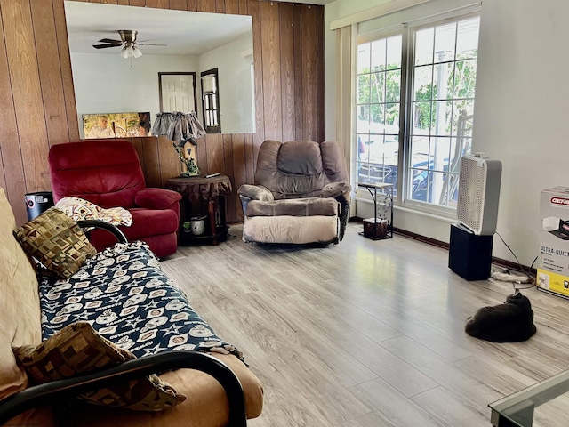 living area with ceiling fan, wood finished floors, a healthy amount of sunlight, and wood walls