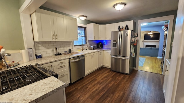 kitchen with a sink, dark wood-style floors, stainless steel appliances, a fireplace, and light countertops