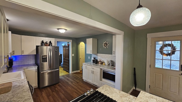 kitchen featuring dark wood finished floors, white cabinetry, arched walkways, appliances with stainless steel finishes, and baseboards