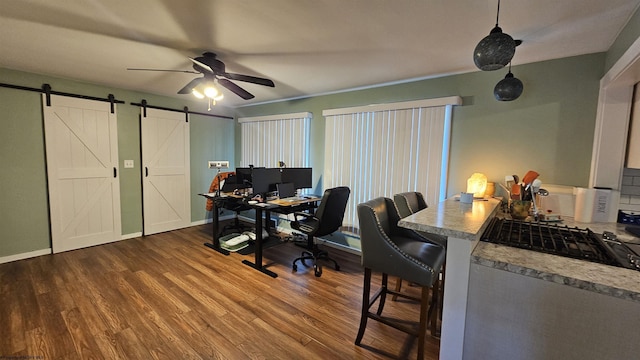 home office with a barn door, baseboards, dark wood-type flooring, and ceiling fan