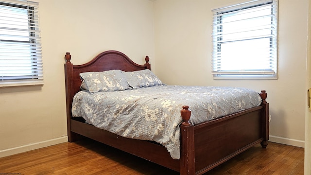 bedroom featuring baseboards, multiple windows, and wood finished floors