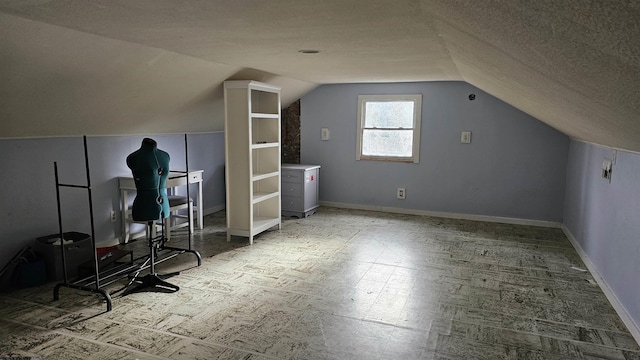 additional living space featuring a textured ceiling, lofted ceiling, and baseboards