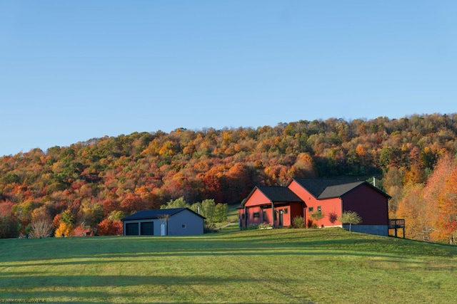 view of front of home featuring a front yard, an outbuilding, a forest view, and a detached garage