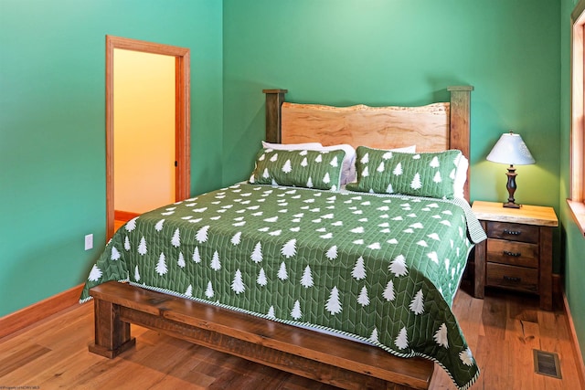 bedroom featuring wood finished floors, visible vents, and baseboards