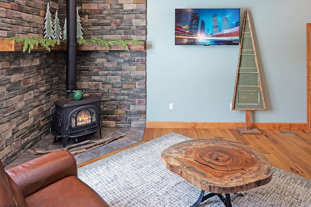 interior space featuring a wood stove, wood finished floors, and baseboards