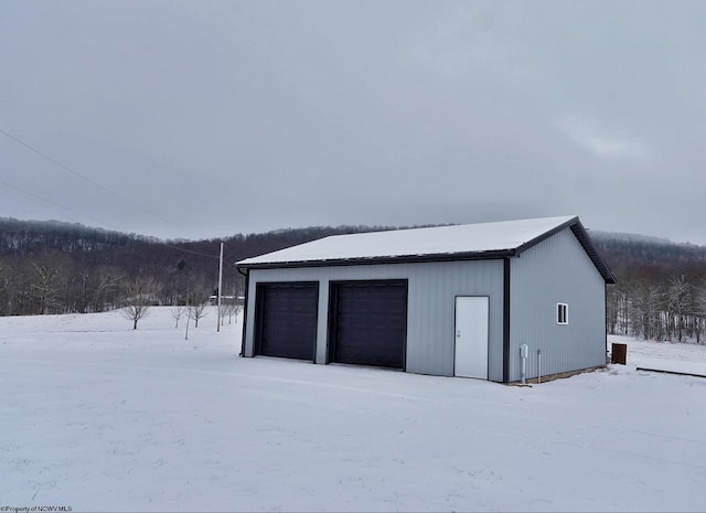 snow covered garage featuring a detached garage