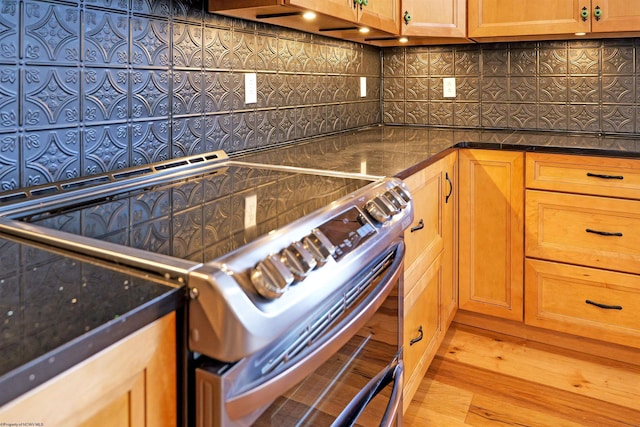 kitchen with electric range, dark countertops, wood finished floors, and decorative backsplash