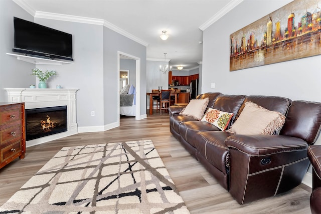 living room with baseboards, a warm lit fireplace, light wood-style flooring, and crown molding