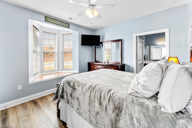 bedroom with ceiling fan, visible vents, baseboards, and wood finished floors