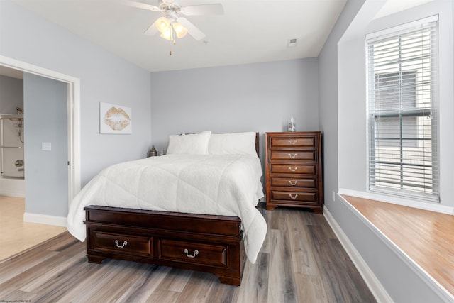 bedroom featuring visible vents, multiple windows, baseboards, and wood finished floors