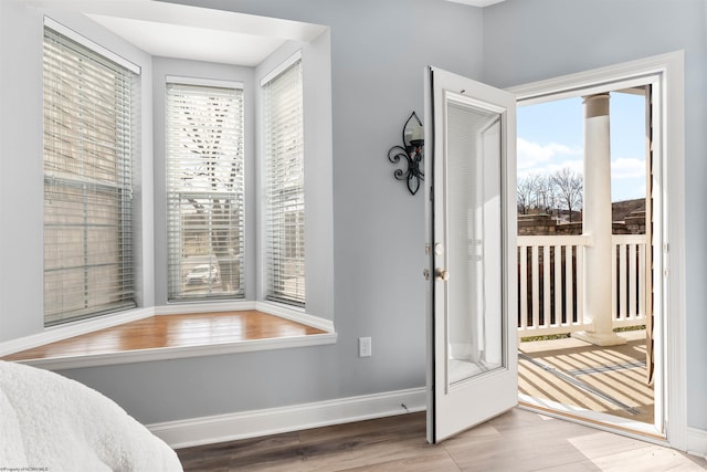 bedroom with access to exterior, baseboards, and wood finished floors