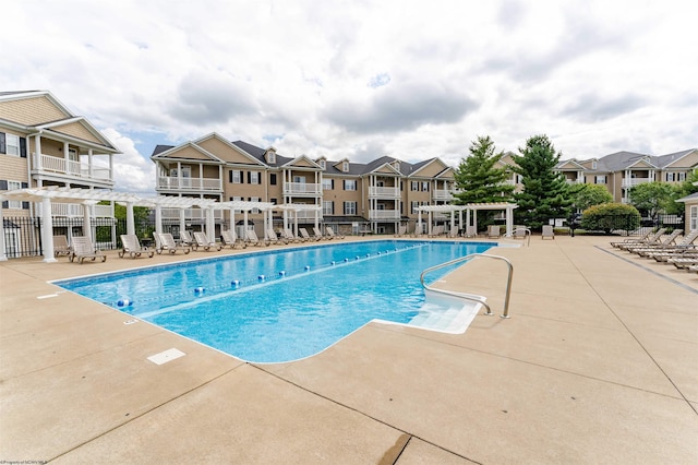 community pool with fence, a patio area, a pergola, and a residential view