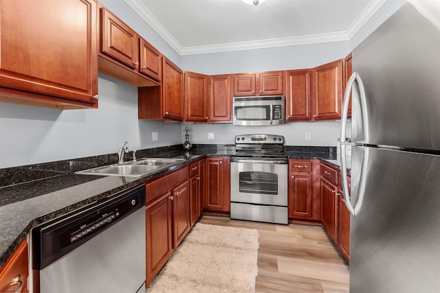 kitchen with a sink, light wood-type flooring, appliances with stainless steel finishes, and ornamental molding