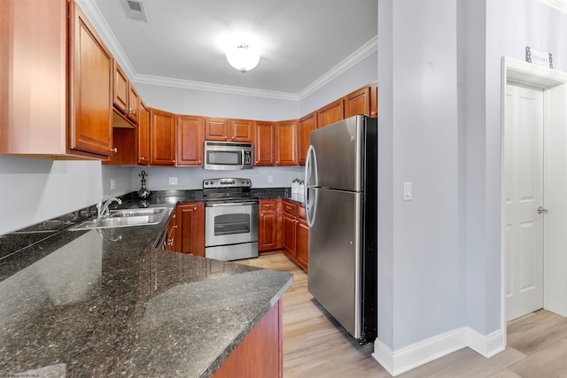 kitchen with light wood-style flooring, ornamental molding, a sink, dark stone counters, and appliances with stainless steel finishes