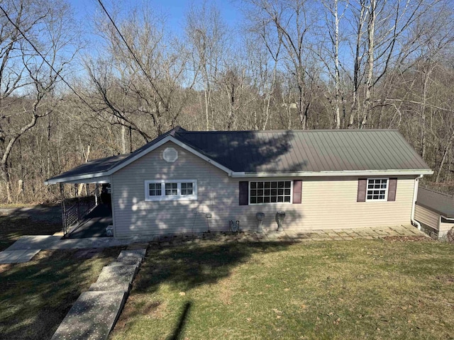 view of front of property featuring a carport, metal roof, and a front lawn