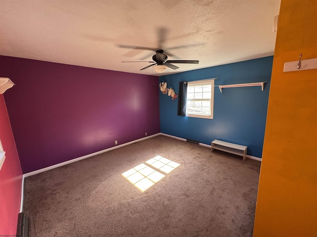 empty room featuring a ceiling fan, baseboards, carpet floors, and a textured ceiling