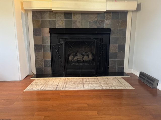 details featuring baseboards, wood finished floors, visible vents, and a fireplace with raised hearth