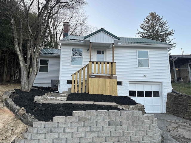 view of front of property featuring cooling unit, driveway, an attached garage, a chimney, and metal roof