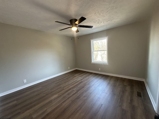 empty room featuring visible vents, dark wood-type flooring, baseboards, a textured ceiling, and a ceiling fan