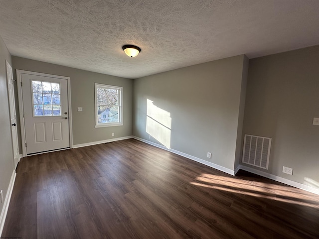 foyer featuring visible vents, a textured ceiling, dark wood-type flooring, and baseboards