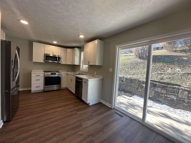 kitchen with visible vents, dark wood finished floors, a sink, stainless steel appliances, and light countertops