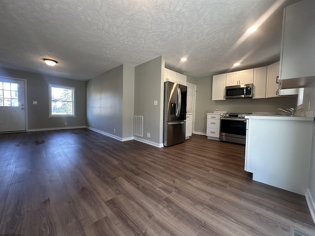 kitchen featuring dark wood finished floors, visible vents, stainless steel appliances, and open floor plan