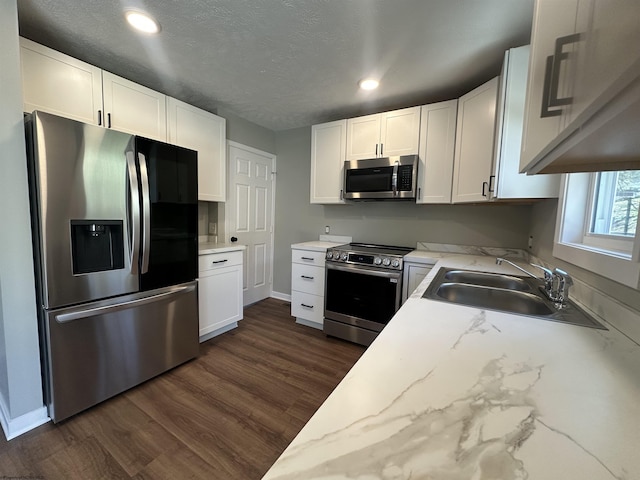 kitchen with dark wood-type flooring, recessed lighting, stainless steel appliances, white cabinetry, and a sink