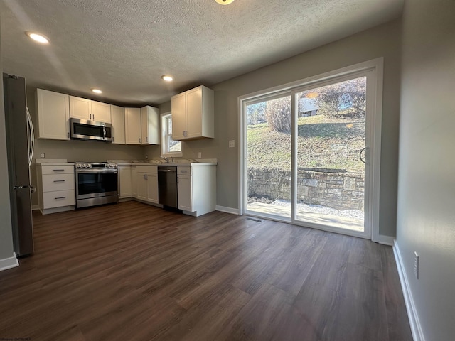 kitchen with white cabinets, stainless steel appliances, light countertops, and dark wood-style flooring