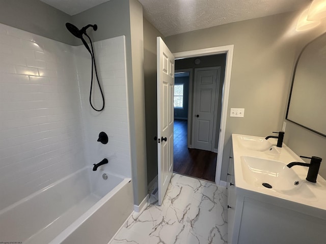 full bath featuring marble finish floor, a textured ceiling, shower / bath combination, and a sink