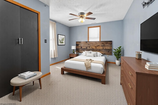 bedroom featuring a textured ceiling, a closet, carpet flooring, baseboards, and ceiling fan